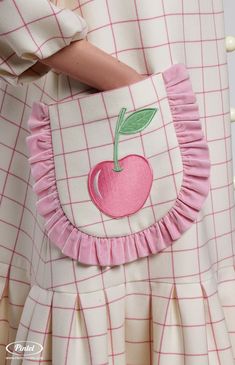 a close up of a person wearing a dress with an apple applique on it