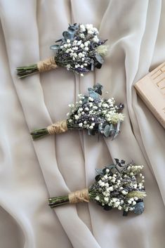 three bridal bouquets with baby's breath are on the white satin fabric