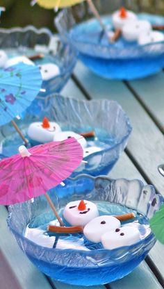 there are some small bowls with marshmallows and umbrellas in them on the table