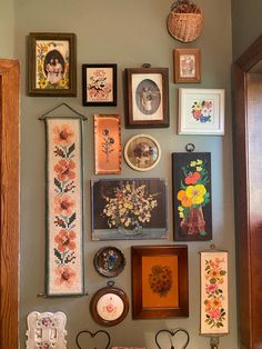 there are many framed pictures on the wall with flowers and other things hanging above them