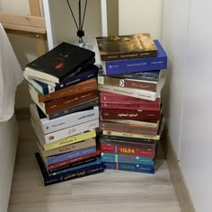 a stack of books sitting on top of a wooden floor next to a white wall