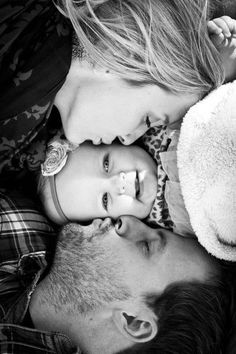 a man and woman laying next to each other on top of a bed with a baby