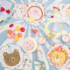 a table topped with lots of paper plates and desserts covered in animal themed decorations