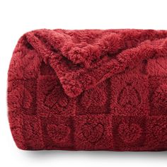 a red blanket that is laying on top of a white surface and it has an intricate design