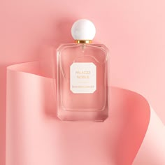 a bottle of perfume sitting on top of a pink surface