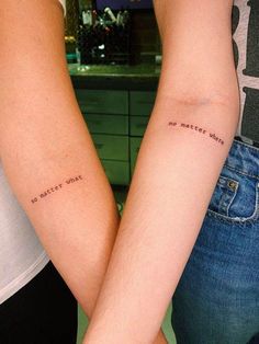 two people with matching tattoos on their arms, one is holding the other's hand