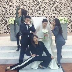 a group of people standing around each other in front of a white chair with flowers on it