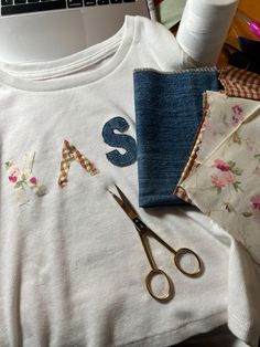 sewing supplies are laid out on top of a table next to a laptop and scissors