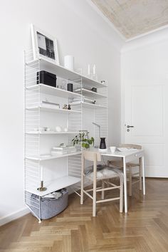 a room with white shelves and chairs in the corner, next to a wooden floor