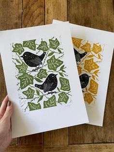 two cards with black birds on them and green leaves in the bottom right hand corner