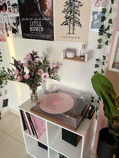 a record player sitting on top of a white shelf next to a potted plant