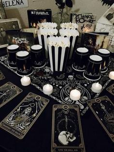 a table topped with cards and candles on top of a black cloth covered tablecloth