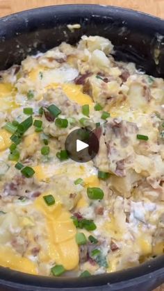 a skillet filled with food on top of a wooden table and topped with green onions