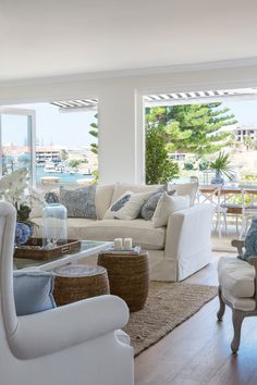 a living room filled with white furniture and lots of windows overlooking the water at night