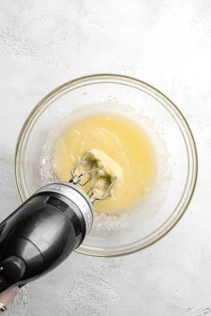 someone mixing batter in a glass bowl with a mixer attachment on the side and an electric hand mixer