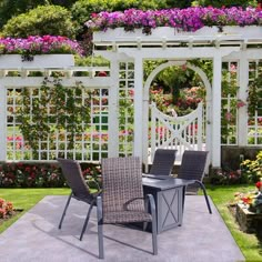 a table and chairs sitting in front of a white trellis