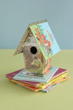 there is a birdhouse on top of many children's books that are stacked up