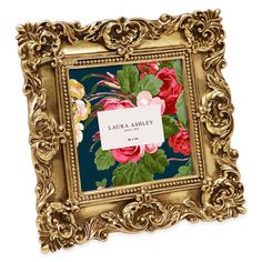 an ornate gold frame with flowers and leaves on the front is holding a label that reads galaa ashley