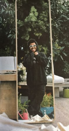 a man wearing sunglasses standing in front of a mirror