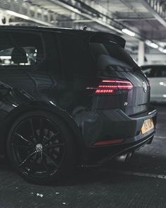 the rear end of a black car parked in a parking garage