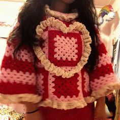 a woman wearing a red and white crocheted sweater with a heart on it