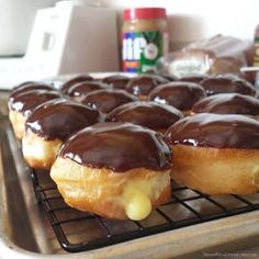 chocolate covered doughnuts cooling on a rack with condiments in the background