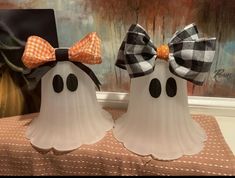 two white ghost statues with black and orange bows