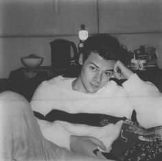 black and white photograph of a young man sitting on a couch with his hand in his hair