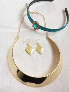 two necklaces and earring sets on a white tablecloth with a blue ribbon