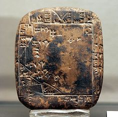 an ancient object with writing on it sitting on top of a block of glass in front of a wall