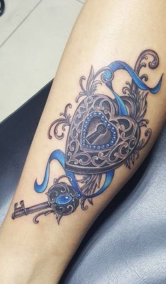 a tattoo on the leg of a woman with a heart and key in it's center