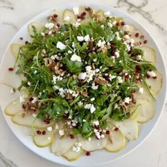 a white plate topped with sliced pears and feta cheese on top of it