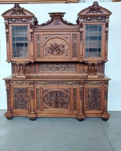 an ornate wooden cabinet with glass doors and carvings on the front, sitting in a room