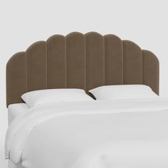 an upholstered headboard on a bed with white sheets