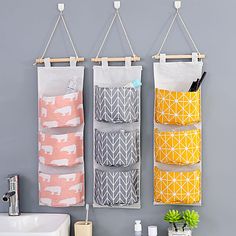 three hanging storage bags on the wall next to a sink