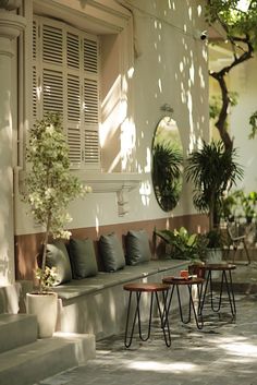 an outdoor seating area with potted plants and round mirrors