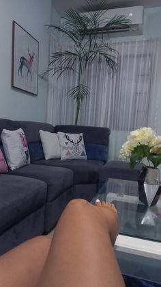 a woman's legs resting on a coffee table in front of a gray couch