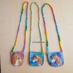 three small purses with horses on them are hanging from a string and decorated with beads