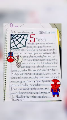 a hand holding up a notebook with writing on it and spiderman drawn on the page