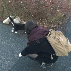 a woman crouches down to pick up her dog