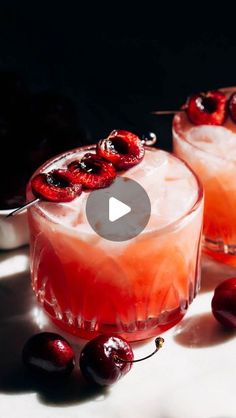 two glasses filled with cherries on top of a table