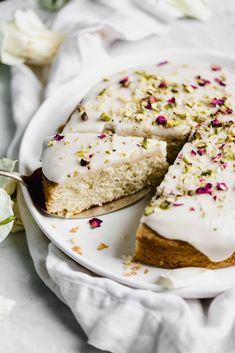 a cake with white frosting and sprinkles on it sitting on a plate