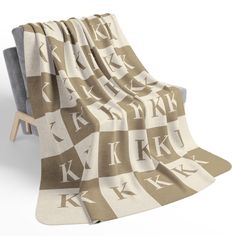 a blanket with the letters k on it is draped over a chair and has a wooden frame