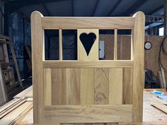 a wooden bed frame with a heart cut out of the front and side panels on top