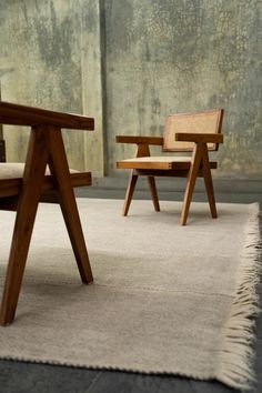 two wooden chairs sitting on top of a rug