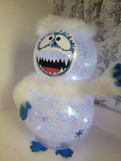 a snowball with a monster face on it's head and arms, sitting in front of a wall