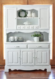 a white china cabinet with dishes on top