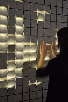 a woman standing in front of a wall covered with lots of cubes and lights