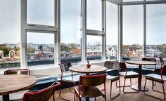 an empty restaurant with tables and chairs near large windows looking out on the city below