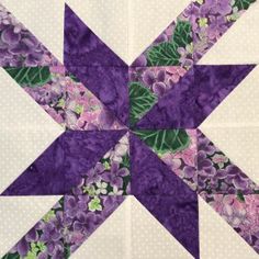 a purple and white quilted star with flowers on the center is featured in this image